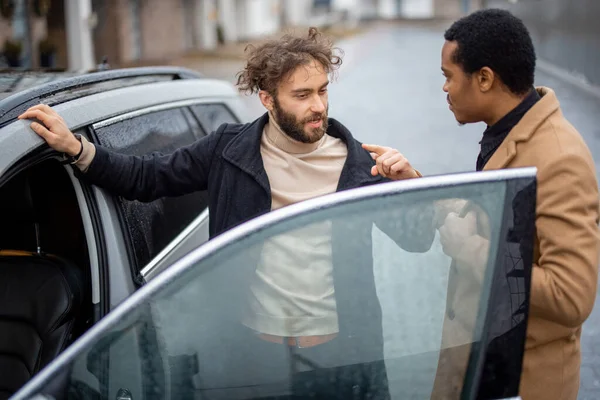 Két férfi flörtöl, miközben a kocsi mellett állnak az utcán. — Stock Fotó