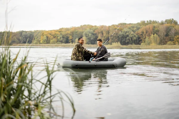 Amis mâles pêchant sur un bateau en caoutchouc dans la rivière — Photo