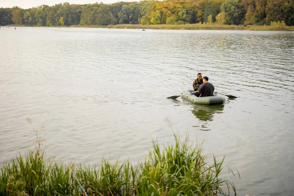 Amis mâles pêchant sur un bateau en caoutchouc dans la rivière — Photo