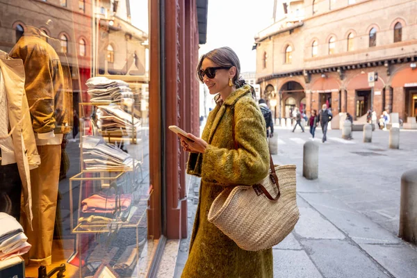 Donna vicino alla vetrina del negozio con abiti di lusso in strada a Bologna — Foto Stock