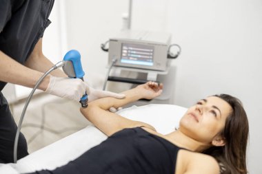 Doktor, kadınların dizlerine şok dalgası tedavisi uyguluyor.