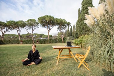 Yeşil çimlerde meditasyon yapan ve yoga yapan bir kız.