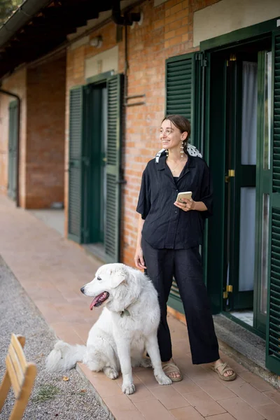 Žena stojící se psem a dívající se stranou u vchodu do hotelového pokoje — Stock fotografie