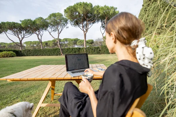 Flicka använda laptop och dricka te vid bordet på gräsmattan — Stockfoto