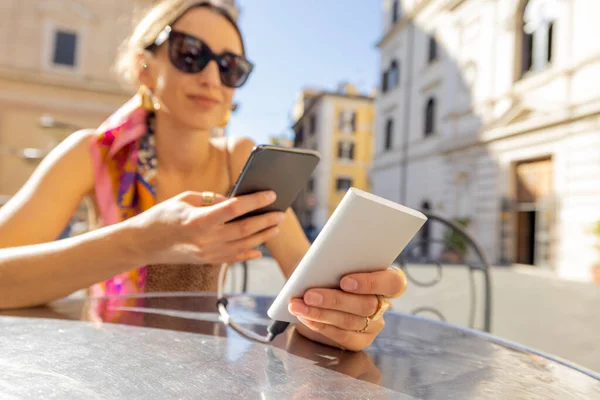Mujer cargando teléfono con un banco de energía en la cafetería al aire libre —  Fotos de Stock