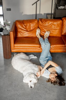 Kadın, sevimli köpeğiyle evdeki kanepenin yanında rahatça uzanıyor.