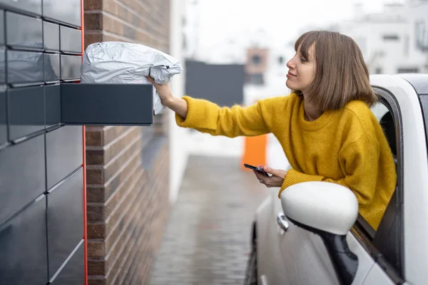Жінка отримує посилку з поштового терміналу прямо з вікна автомобіля на ходу — стокове фото
