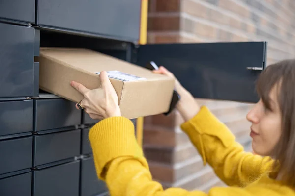 Donna che ottiene pacco dalla cella del terminale postale automatico all'aperto — Foto Stock