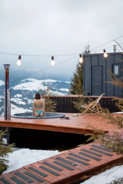 Kadınlar sıcak küvette yüzerken dağlardaki küçük modern evlerde dinleniyorlar. — Stok fotoğraf