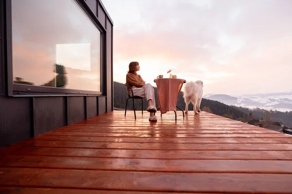 Kvinne med hund som hviler i et lite hus i fjellet. – stockfoto