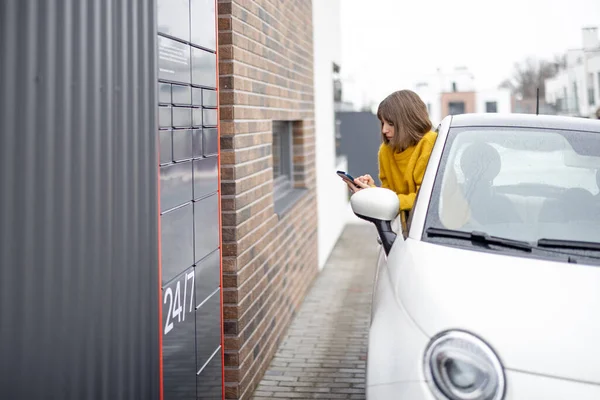 Egy nő kinyitja a postafiókját, okostelefonnal, egyenesen a kocsi ablakából. — Stock Fotó