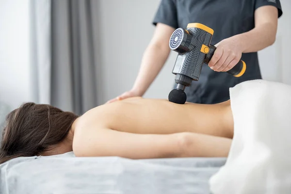 Жінка масажує пацієнтів з ударним масажером — стокове фото