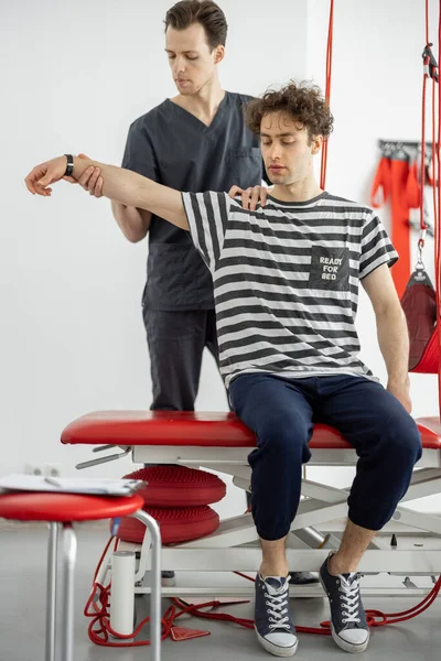 Fysiotherapeut onderzoekt jonge mannelijke patiënt in kliniek — Stockfoto