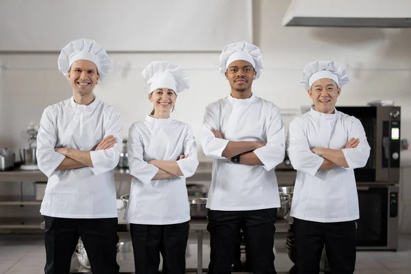 Retrato de un joven grupo multirracial de cocineros de pie juntos en la cocina del restaurante — Foto de Stock