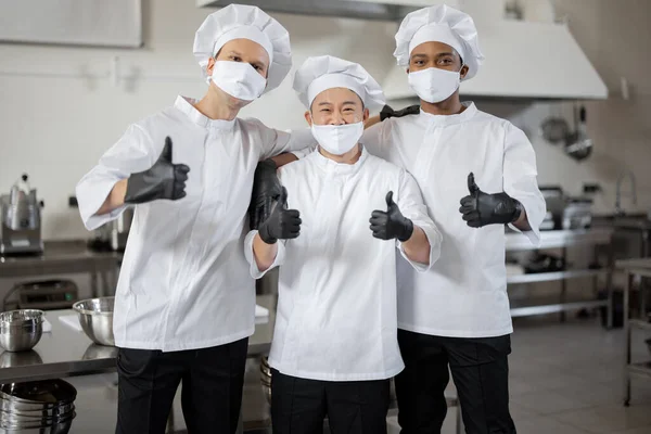 Retrato de equipe multirracial de três chefs juntos na cozinha — Fotografia de Stock