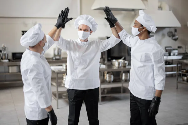 Multiraciale team van chef-koks geven vijf met de handen voor een baan op de keuken — Stockfoto