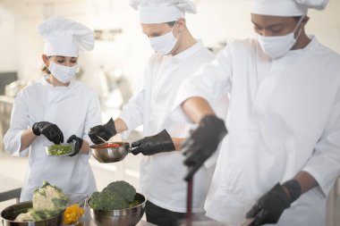 Aşçılardan oluşan çok ırklı bir ekip mutfakta birlikte yemek pişiriyor.