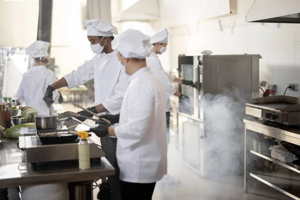 Equipo multirracial de cocineros cocineros cocinando juntos en la cocina —  Fotos de Stock