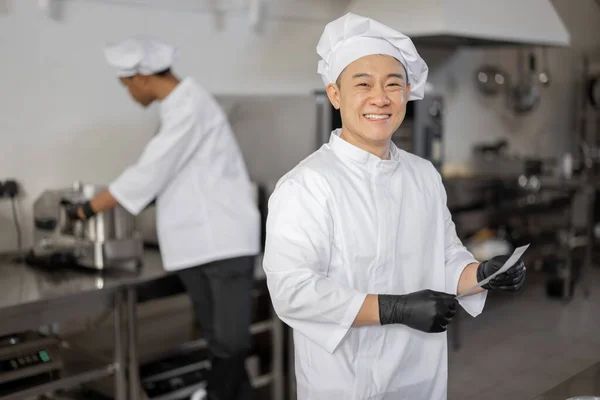 부엌에서 유니폼을 입은 아시아인 요리사의 웃는 모습 — 스톡 사진