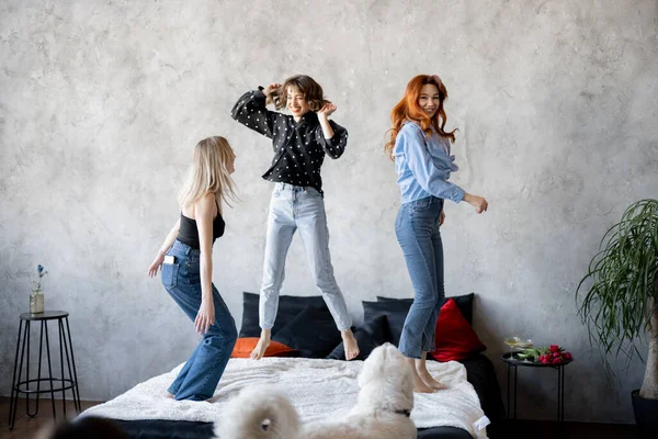 Erwachsene Freundinnen haben Spaß, springen zusammen auf dem Bett zu Hause — Stockfoto