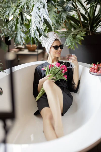 Vrouw liggend in bad met een boeket tulpen — Stockfoto