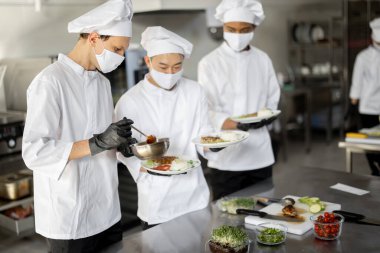 Mutfaktaki bir restoran için hazır yemeklerle bekleyen çok ırklı aşçılar.
