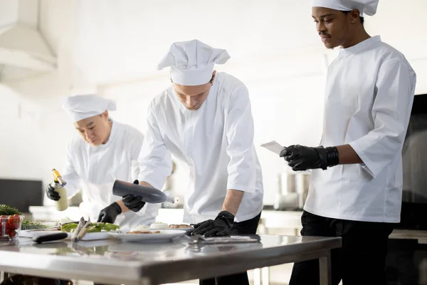 Groep koks die hoofdgerechten afwerken terwijl ze samenwerken in de keuken — Stockfoto