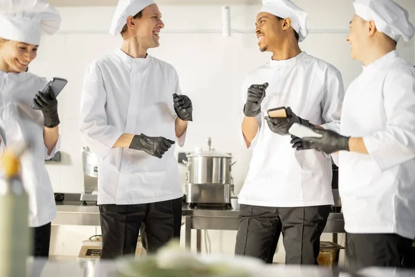 Equipe de cozinheiros multirraciais conversando durante uma pausa para café na cozinha — Fotografia de Stock