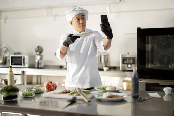 Chef asiático gravar um vlog culinária no telefone na cozinha — Fotografia de Stock