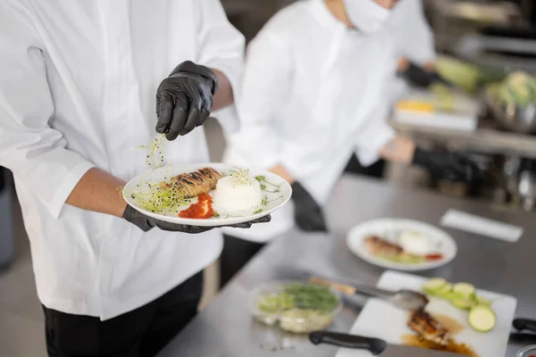 Cocinas terminando platos principales en la cocina del restaurante —  Fotos de Stock