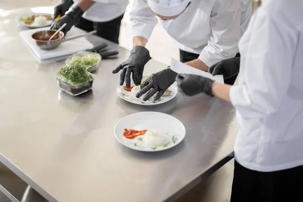 Cooks finishing main courses in the restaurant kitchen — Stock Photo, Image