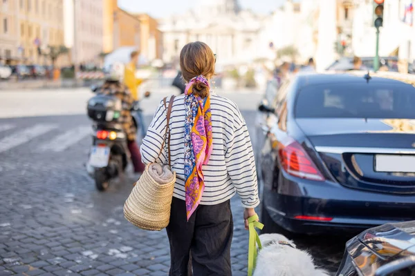 Tyylikäs nainen kävelee koiran kanssa kadulla Roomassa — kuvapankkivalokuva