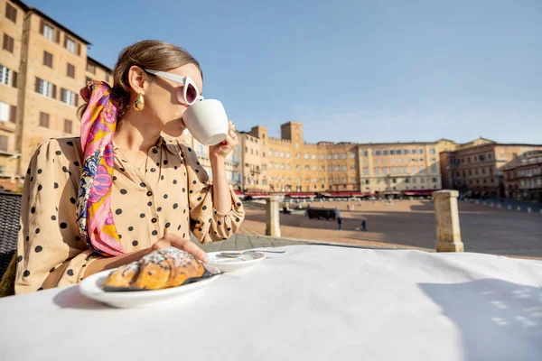 이탈리아 시에나 시의 중심가에서 아름다운 경치를 간직 한 옥외 카페에서 아침 식사를 하고 있는 여자 — 스톡 사진