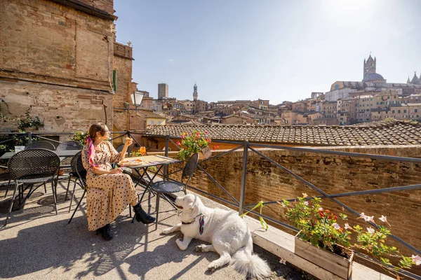 Giovane donna a pranzo, seduta con un cane al ristorante all'aperto della città di Siena — Foto Stock