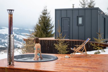 Kadınlar sıcak küvette yüzerken dağlardaki küçük modern evlerde dinleniyorlar.