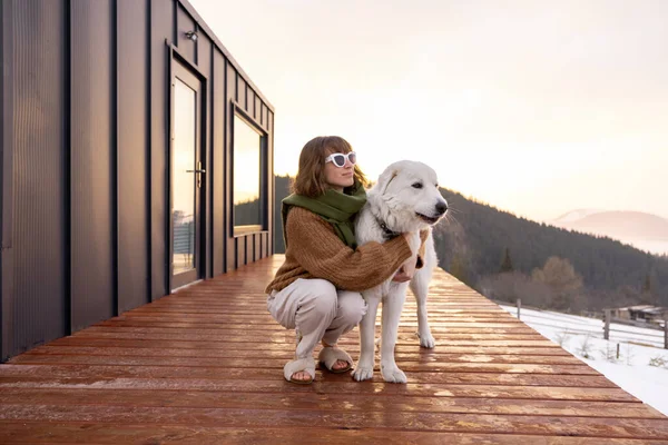 개와 함께 자연계에 있는 작은 집 테라스 위에 앉아 있는 여자 — 스톡 사진