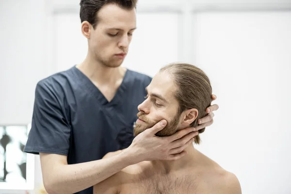 Fisioterapeuta faz terapia manual para um jovem atlético em consultório médico — Fotografia de Stock