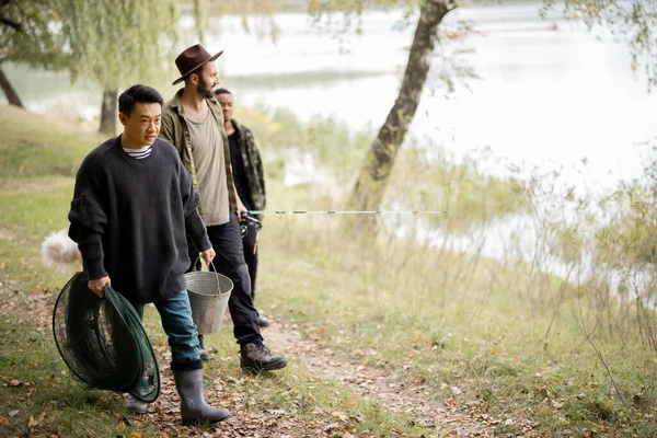 Les hommes marchent avec chien et équipement de pêche dans la nature — Photo