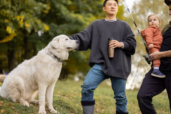 Multiracial amis masculins repos avec chien dans la nature à l'automne — Photo