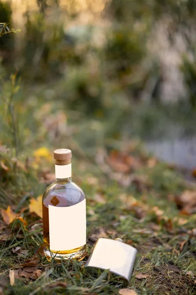 Bottle and flask on the grass at picnic — Stock Photo, Image