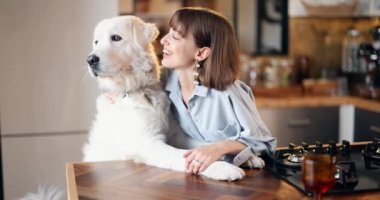 Evde yemek pişirirken koca köpeğini besleyen bir kadın.