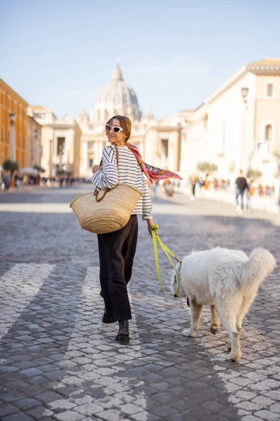 Roma 'da şık bir kadın bir köpekle sokakta yürüyor.