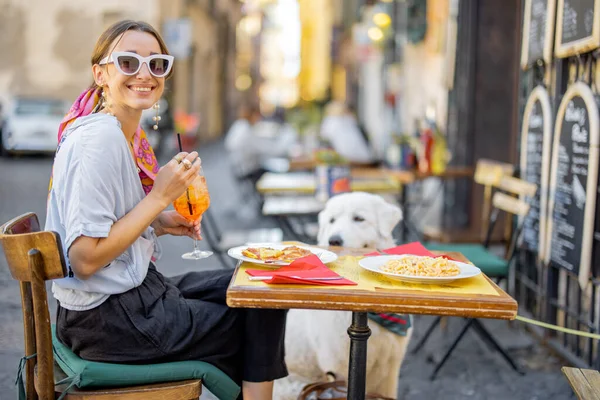 Donna che mangia pasta italiana seduta con un cane al ristorante per strada a Roma — Foto Stock