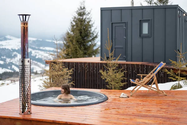 Kobieta pływa w gorącej kąpieli podczas odpoczynku w małym nowoczesnym domu w górach — Zdjęcie stockowe
