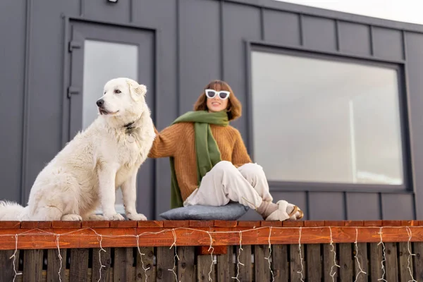 Kvinna med sin hund vilar på terrassen av litet hus på naturen — Stockfoto