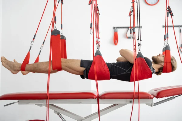 Male patient hanging on suspensions at rehabilitation center — Stock Photo, Image