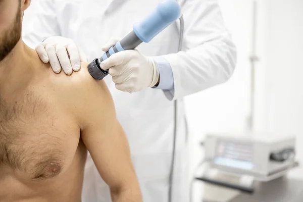 Legen påfører sjokkbølgeterapi på menn skulder – stockfoto