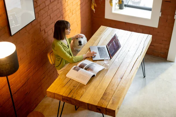 Woman works on laptop while sitting by the wooden table in cozy living room — Stock Photo, Image