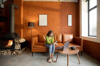 Kadın, modern oturma odasında aletlerle oturuyor. Çatı katı tarzında.