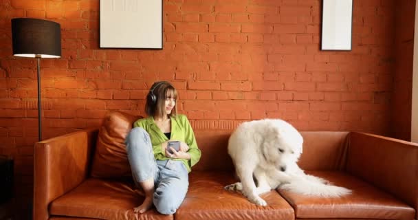 A nő otthon ölelkezik a fehér imádnivaló kutyájával. — Stock videók